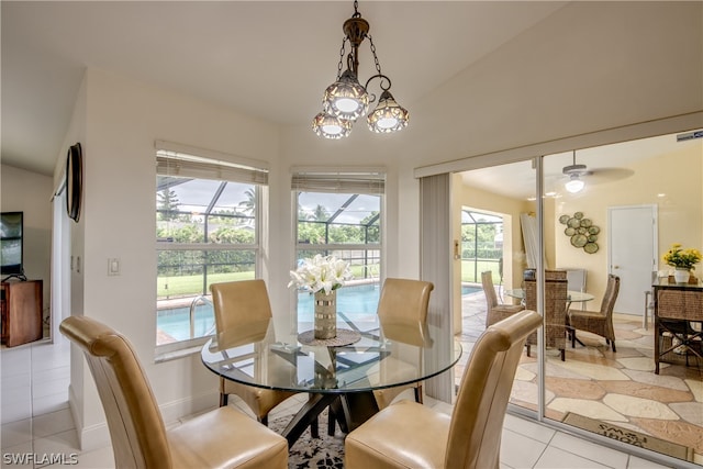 dining room featuring ceiling fan with notable chandelier, vaulted ceiling, and light tile patterned floors