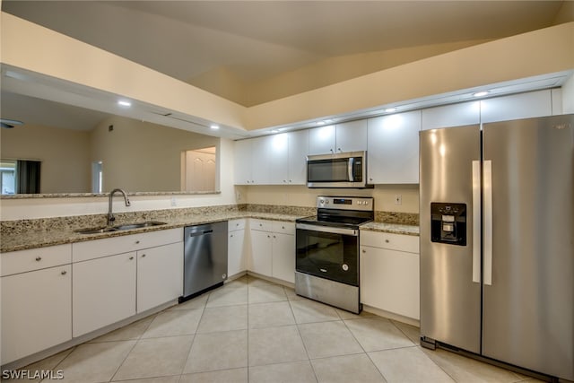 kitchen with stainless steel appliances, lofted ceiling, white cabinets, light stone counters, and sink