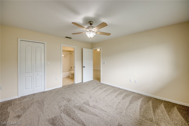 unfurnished bedroom with ceiling fan, ensuite bathroom, a closet, and carpet floors