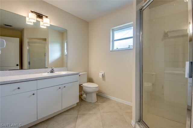 bathroom featuring toilet, vanity, tile patterned floors, and a shower with door