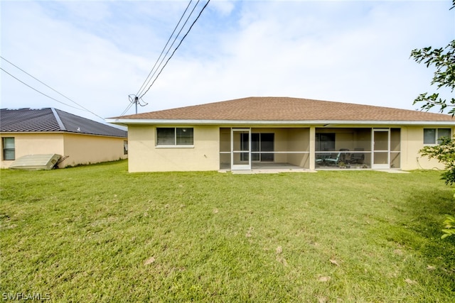 back of house featuring a lawn and a sunroom