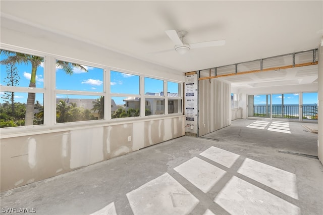 unfurnished sunroom featuring a water view, a wealth of natural light, and ceiling fan