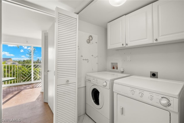 washroom featuring cabinets, washing machine and clothes dryer, and light wood-type flooring