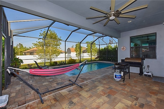 view of swimming pool featuring grilling area, ceiling fan, a patio, and glass enclosure