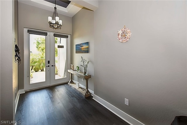 foyer featuring dark wood-type flooring, a notable chandelier, and french doors