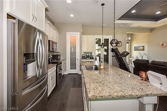 kitchen featuring decorative light fixtures, stainless steel appliances, dark hardwood / wood-style flooring, sink, and a spacious island