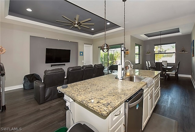 kitchen with a wealth of natural light, an island with sink, ceiling fan, and a tray ceiling