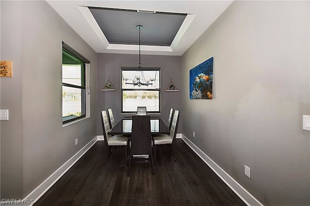 dining room with dark hardwood / wood-style flooring, a raised ceiling, and a notable chandelier