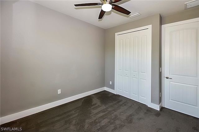 unfurnished bedroom with ceiling fan, dark colored carpet, and a closet