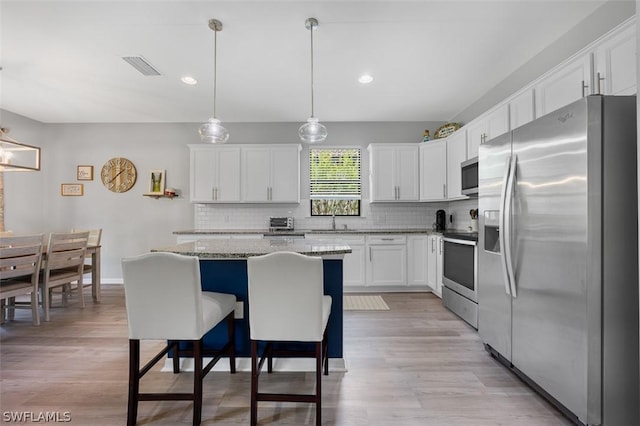 kitchen with a kitchen island, pendant lighting, white cabinetry, decorative backsplash, and stainless steel appliances