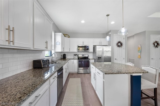 kitchen with stainless steel appliances, white cabinetry, a center island, and sink