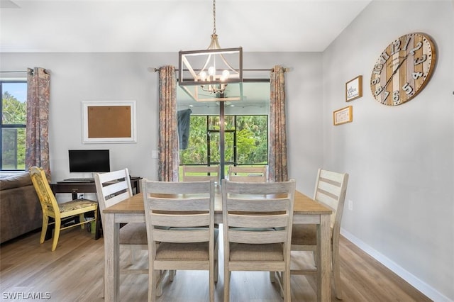 dining area with light hardwood / wood-style flooring and a notable chandelier