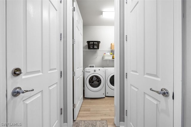 laundry room with washer and clothes dryer and light hardwood / wood-style flooring