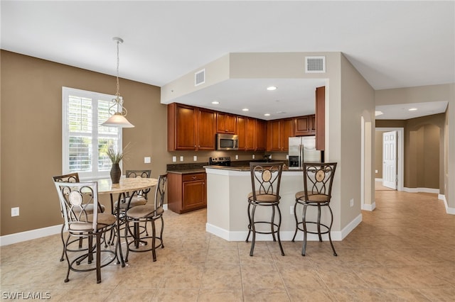 kitchen with a breakfast bar, pendant lighting, stainless steel appliances, and light tile patterned flooring