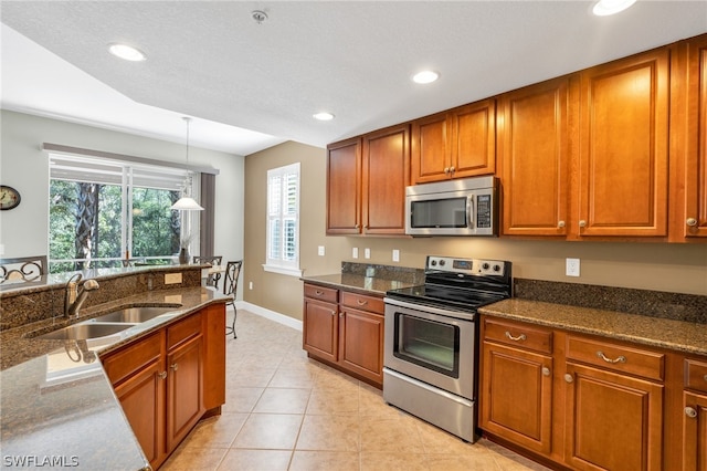 kitchen featuring dark stone countertops, pendant lighting, sink, stainless steel appliances, and light tile patterned floors