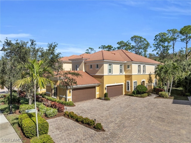 mediterranean / spanish-style house featuring stucco siding, a tile roof, and decorative driveway