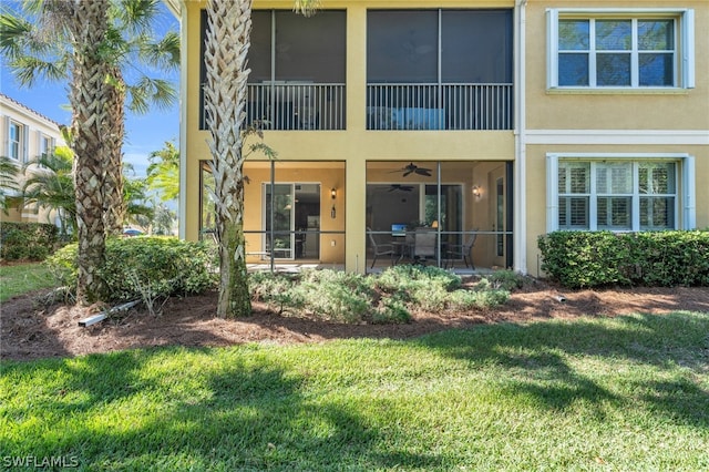 back of property with ceiling fan, a yard, and a patio