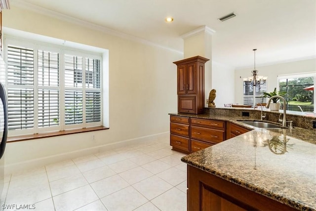 kitchen with light tile patterned floors, a sink, visible vents, dark stone countertops, and crown molding