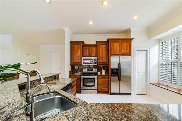 kitchen featuring light tile patterned floors, decorative backsplash, appliances with stainless steel finishes, a sink, and dark stone counters