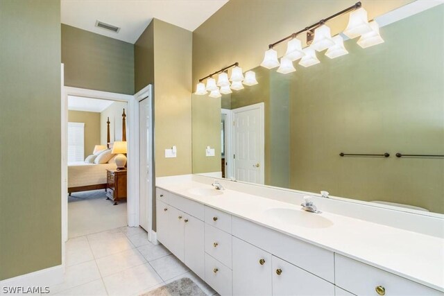 ensuite bathroom featuring double vanity, visible vents, tile patterned flooring, and a sink