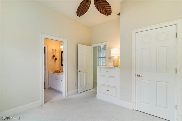 bedroom featuring ensuite bathroom, baseboards, and light colored carpet