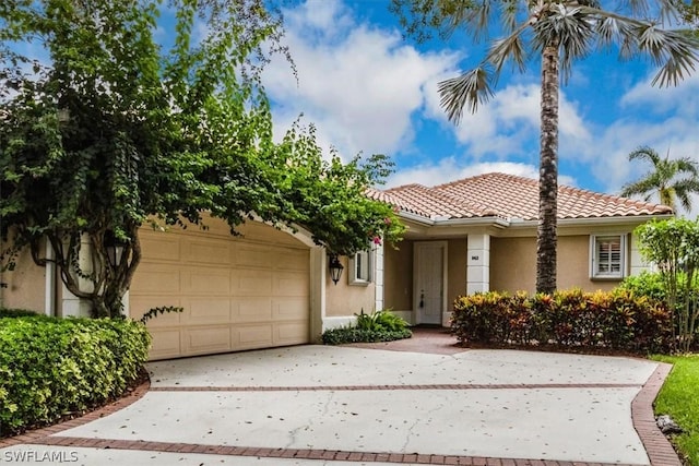 view of front of property featuring stucco siding, a tiled roof, concrete driveway, and a garage