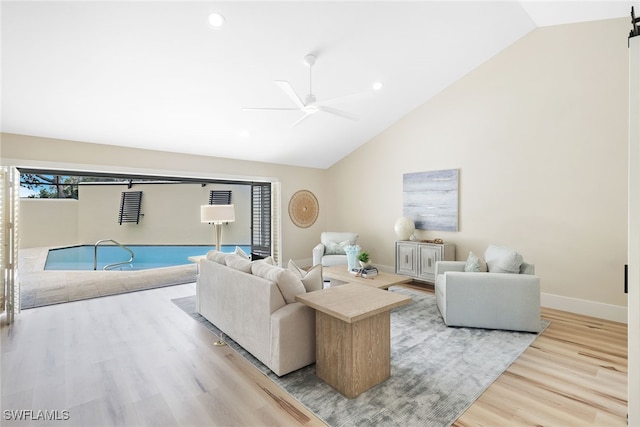 living room featuring a barn door, ceiling fan, light wood-type flooring, and lofted ceiling