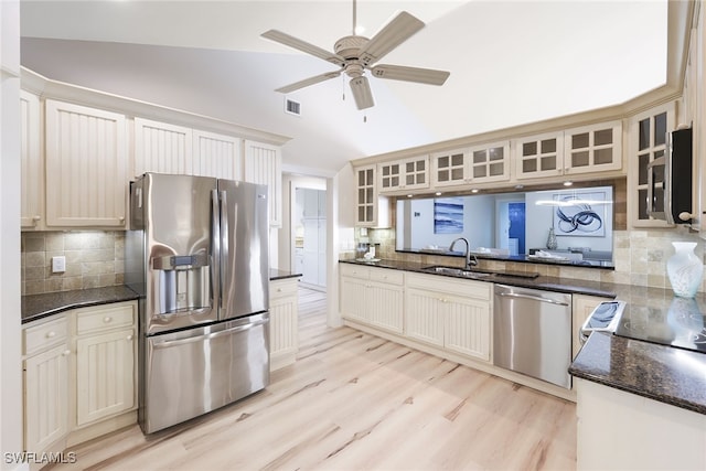 kitchen featuring sink, appliances with stainless steel finishes, backsplash, light hardwood / wood-style flooring, and lofted ceiling