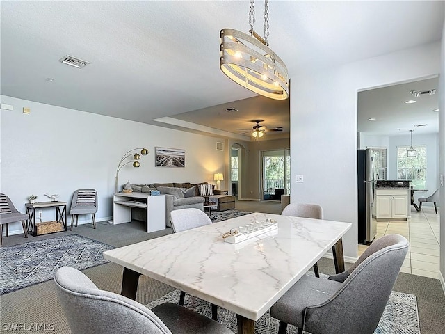 dining area with ceiling fan, a tray ceiling, light colored carpet, and a wealth of natural light