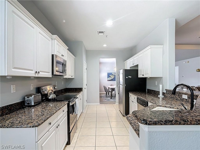 kitchen with appliances with stainless steel finishes, kitchen peninsula, and white cabinets