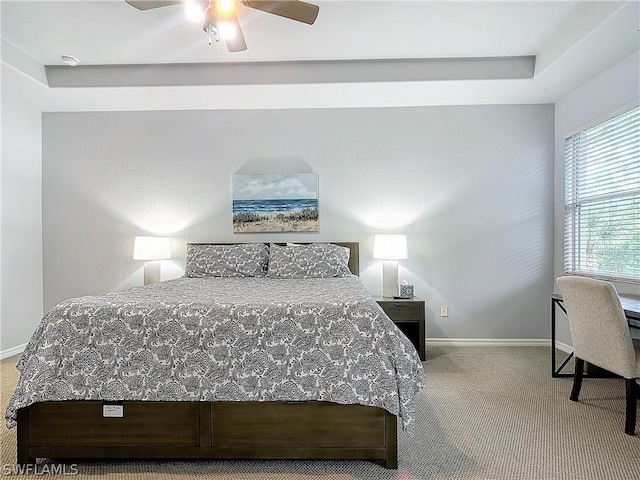 bedroom with ceiling fan, a tray ceiling, and light carpet