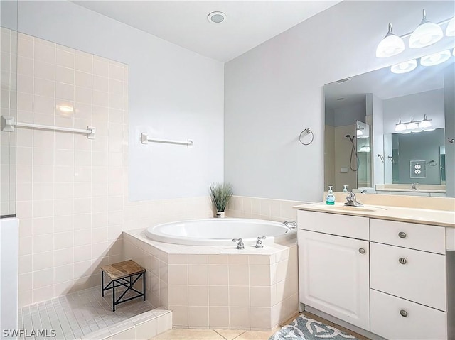 bathroom featuring a relaxing tiled tub and vanity