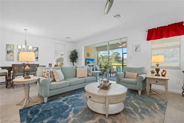 tiled living room with ceiling fan with notable chandelier