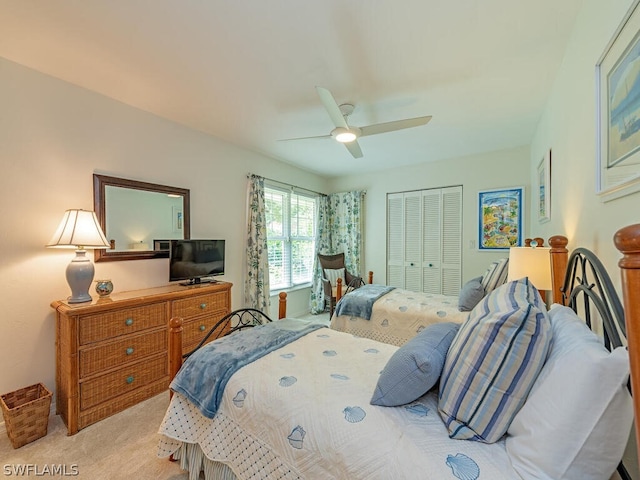 bedroom with ceiling fan, light carpet, and a closet