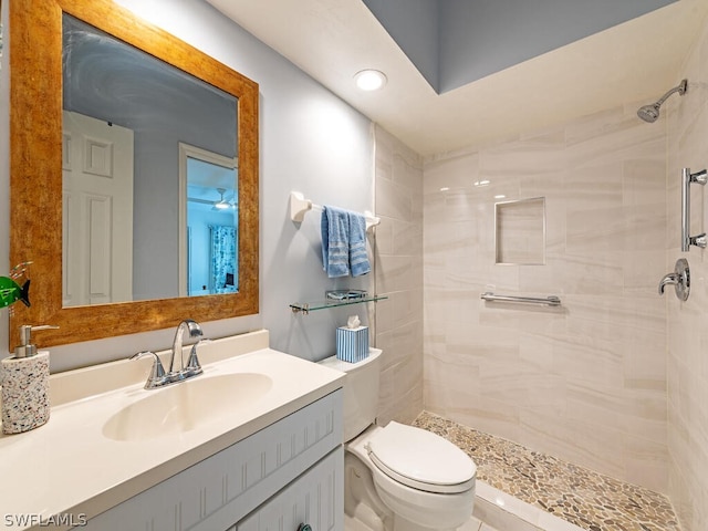 bathroom featuring a tile shower, vanity, and toilet