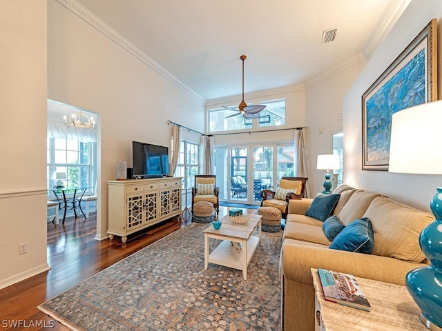 living room featuring a high ceiling, crown molding, dark wood-type flooring, and ceiling fan with notable chandelier