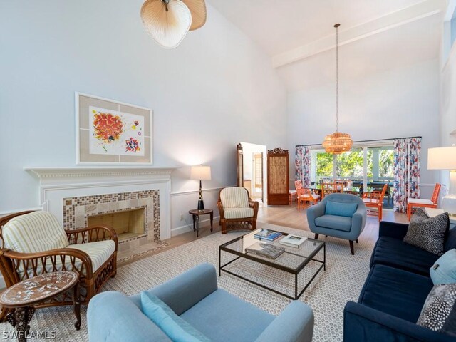 living room with high vaulted ceiling, a tile fireplace, and light hardwood / wood-style flooring