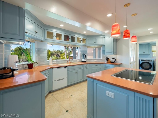 kitchen featuring pendant lighting, washing machine and clothes dryer, backsplash, black stovetop, and white dishwasher