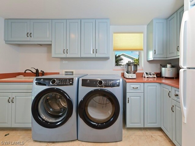 clothes washing area with cabinets, sink, light tile patterned floors, and washing machine and dryer