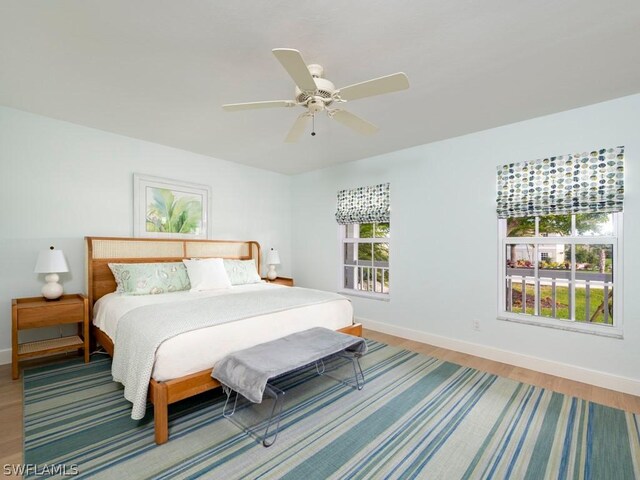 bedroom featuring ceiling fan, multiple windows, and hardwood / wood-style flooring