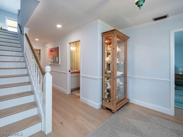 staircase with hardwood / wood-style flooring and crown molding