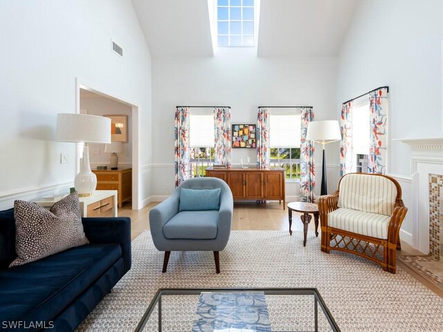 living room with high vaulted ceiling and light hardwood / wood-style flooring