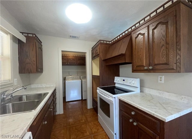 kitchen with sink, washer and dryer, white range with electric cooktop, and dark brown cabinets