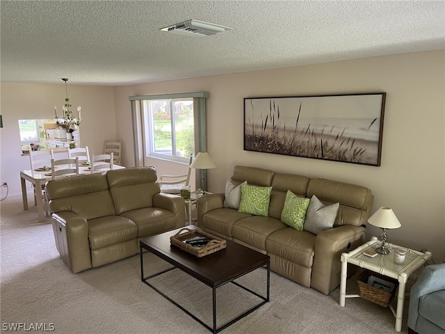 carpeted living room with a notable chandelier and a textured ceiling