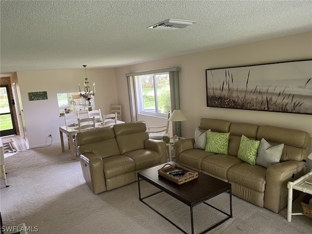 carpeted living room featuring a notable chandelier and a textured ceiling