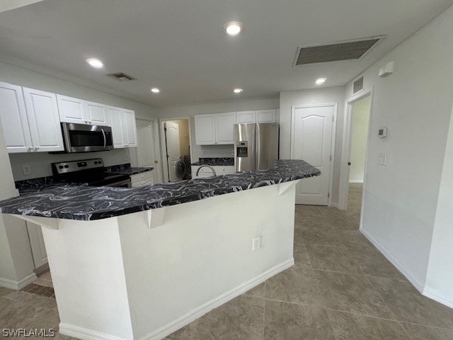 kitchen featuring white cabinetry, stainless steel appliances, kitchen peninsula, a kitchen bar, and light tile patterned floors