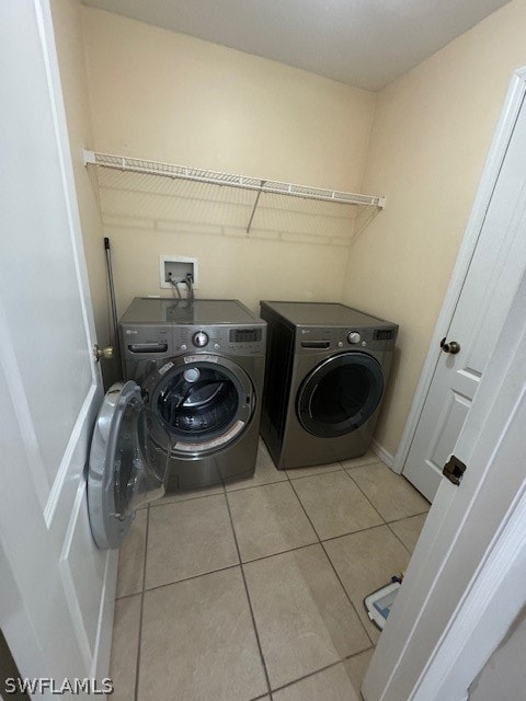 laundry room with washing machine and clothes dryer and light tile patterned floors