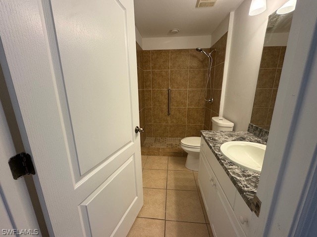 bathroom featuring tile patterned floors, toilet, vanity, and a tile shower