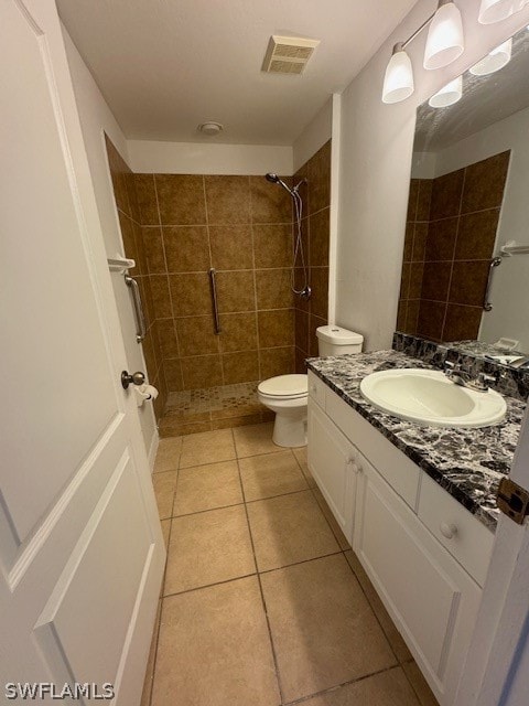 bathroom featuring tile patterned floors, vanity, a tile shower, and toilet