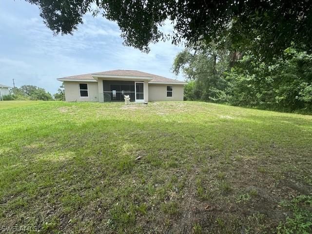 2813 52nd St W, Lehigh Acres, FL 33971 - rear view of property with a yard and stucco siding